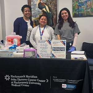 Three team members standing behind a colorectal cancer screening information table